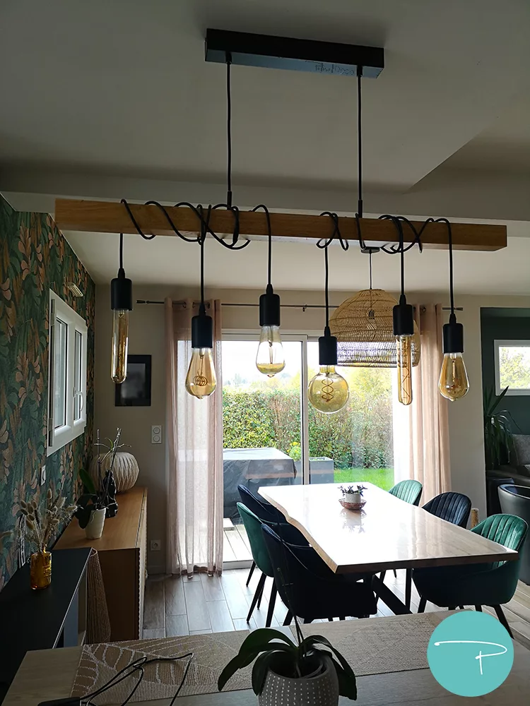 Salon, salle à manger et entrée à la décoration au style bohème chaleureux, cosy et coloré avec papier peint naturel vert, terracotta et jaune ocre. Murs vert dans salon et jaune ocre dans l'entrée. Mobilier en bois, suspension et lampadaire en fibre naturelle et chaises velours noir et vert